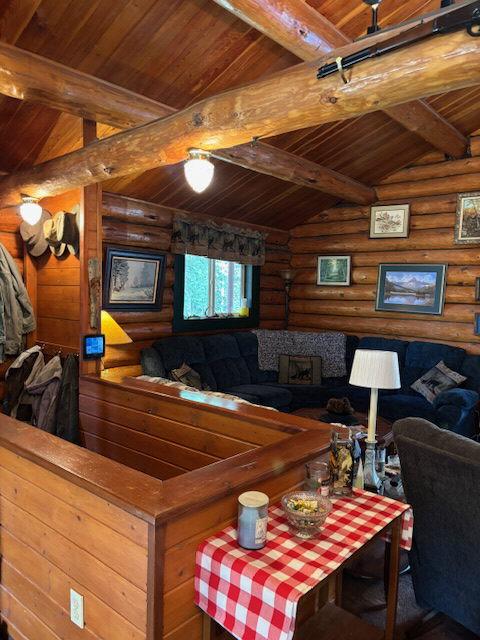 living room with rustic walls, vaulted ceiling with beams, and wooden ceiling