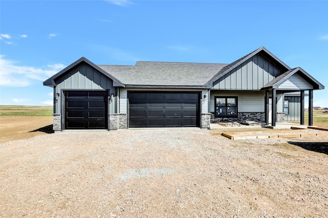 modern inspired farmhouse with roof with shingles, stone siding, board and batten siding, and a garage