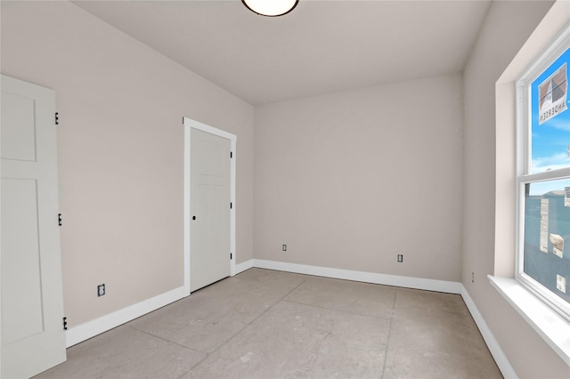 empty room featuring concrete floors and baseboards