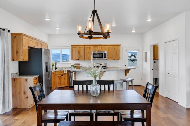 dining area featuring recessed lighting, light wood-style flooring, and a notable chandelier