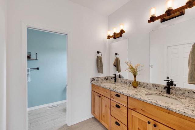 full bathroom with double vanity, visible vents, baseboards, and a sink
