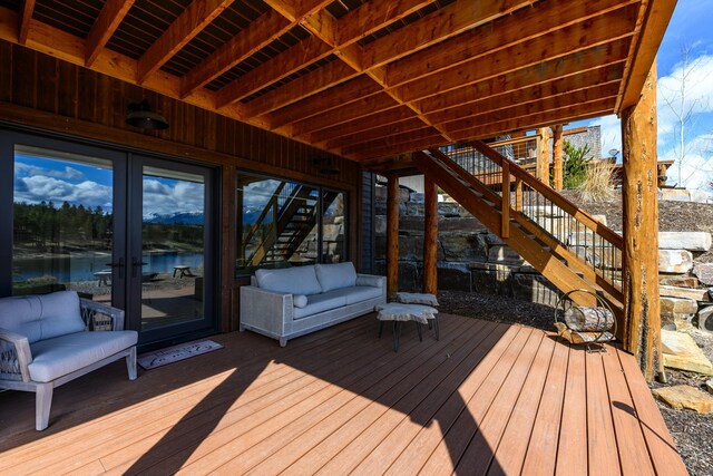 deck featuring stairway, french doors, and a water view