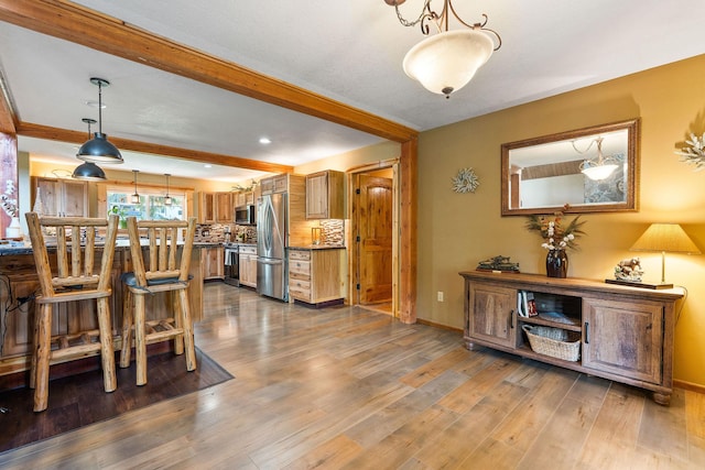 dining area featuring wood finished floors, beam ceiling, and baseboards