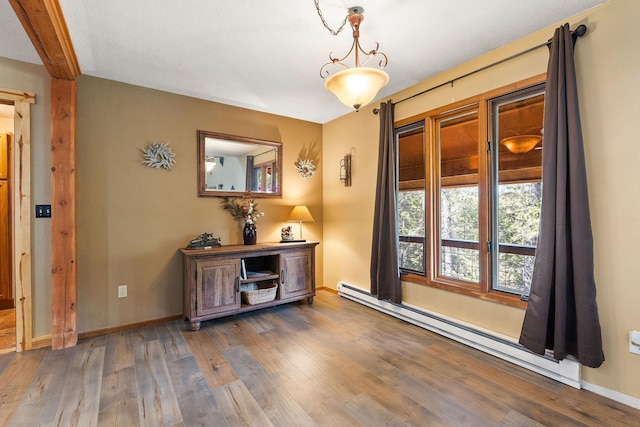 interior space with baseboard heating, baseboards, and wood finished floors