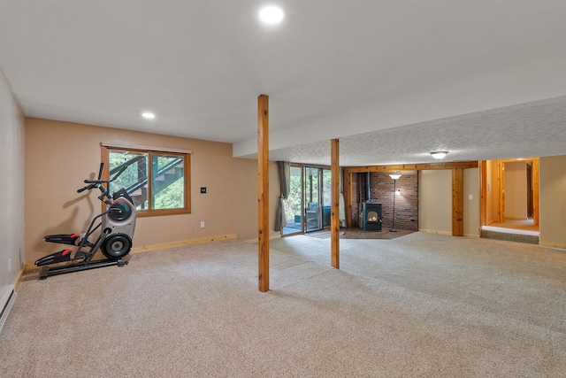 below grade area with recessed lighting, a wood stove, carpet flooring, and baseboards
