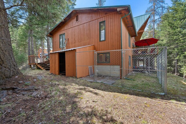 back of house with metal roof, fence, and a deck