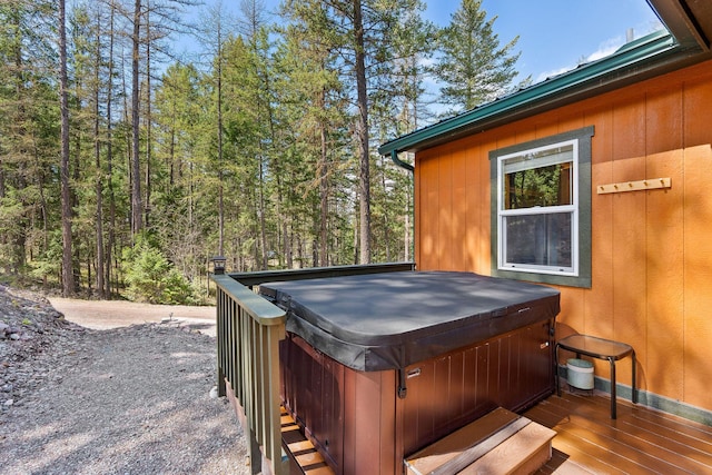 wooden terrace with a view of trees and a hot tub