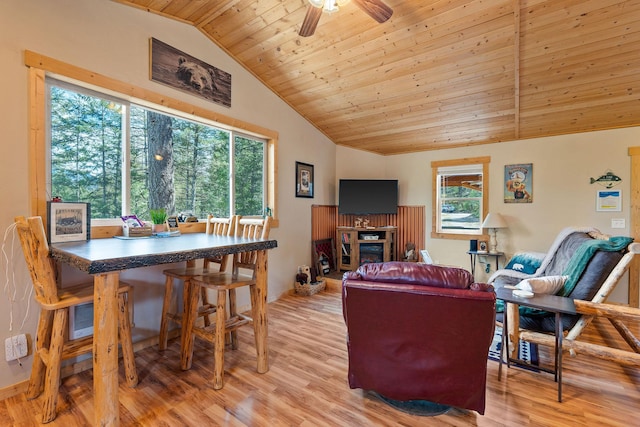 living room featuring lofted ceiling, a ceiling fan, wooden ceiling, light wood-style floors, and a glass covered fireplace