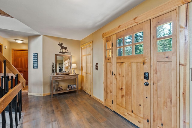entrance foyer with stairway, dark wood finished floors, and baseboards
