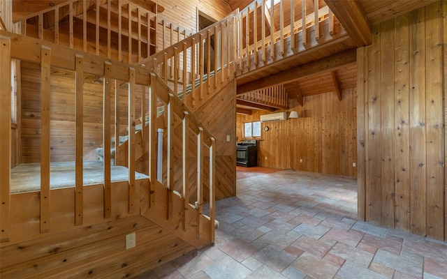 1298 E Mountain Meadow Rd, Kalispell, MT 59901 - staircase with wood walls, stone tile flooring, a wall mounted air conditioner, and beamed ceiling