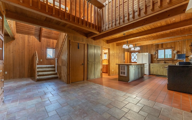 1298 E Mountain Meadow Rd, Kalispell, MT 59901 - kitchen featuring freestanding refrigerator, beam ceiling, wooden walls, plenty of natural light, and a center island