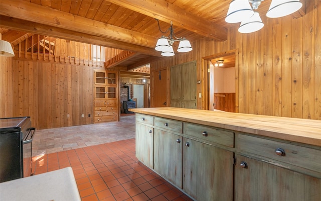 1298 E Mountain Meadow Rd, Kalispell, MT 59901 - kitchen featuring wooden counters, wood walls, a chandelier, a wooden ceiling with exposed beams, and a wood stove