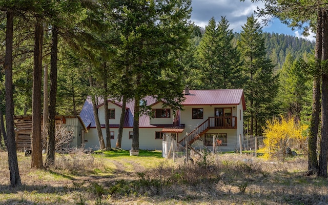 1298 E Mountain Meadow Rd, Kalispell, MT 59901 - view of front of house with stairs, a metal roof, and a forest view