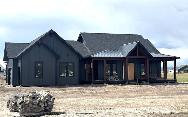 view of front of home with roof with shingles, metal roof, an outdoor fire pit, and covered porch