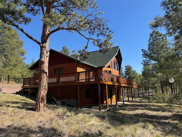 back of house featuring log veneer siding, a shingled roof, and a deck