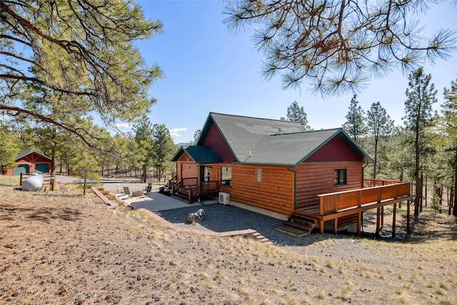 view of property exterior featuring a wooden deck, a shingled roof, and log veneer siding