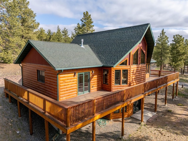 rear view of house featuring roof with shingles, a wooden deck, and faux log siding