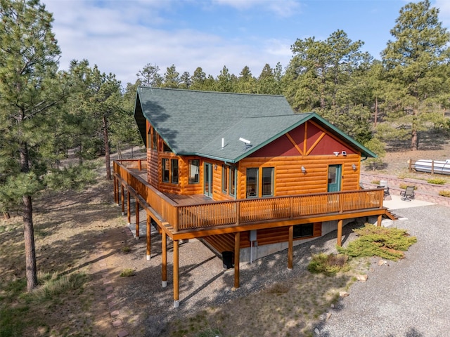 back of property featuring a wooden deck, roof with shingles, and faux log siding