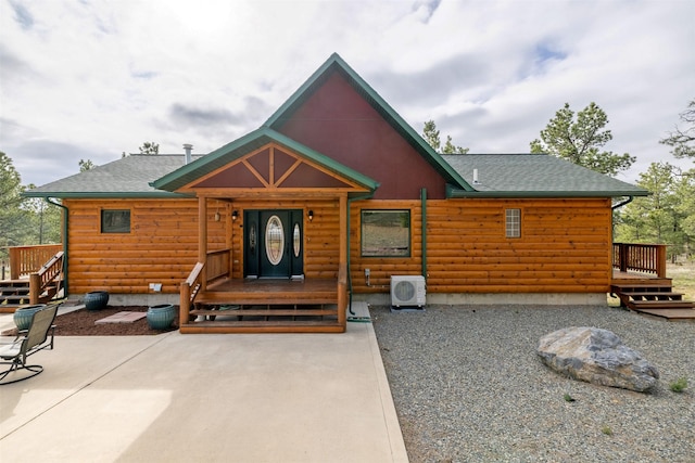view of front of house with ac unit, a patio area, roof with shingles, and faux log siding