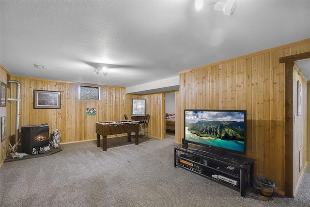 3404 Jasper Rd, Great Falls, MT 59404 - recreation room featuring a wood stove, wooden walls, carpet flooring, and a textured ceiling