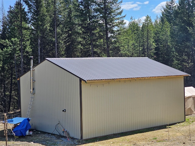 view of outdoor structure featuring a wooded view and an outbuilding