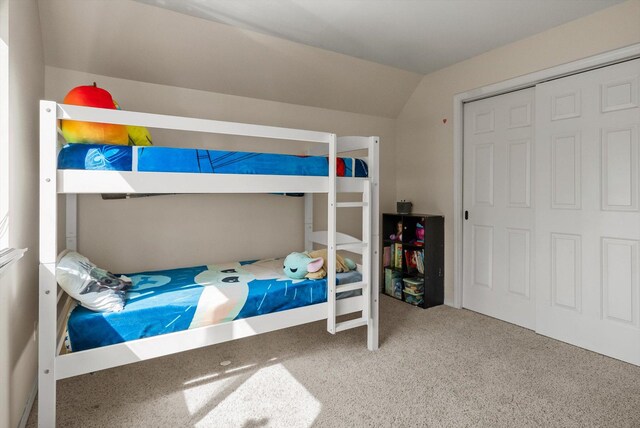 carpeted bedroom featuring a closet and vaulted ceiling