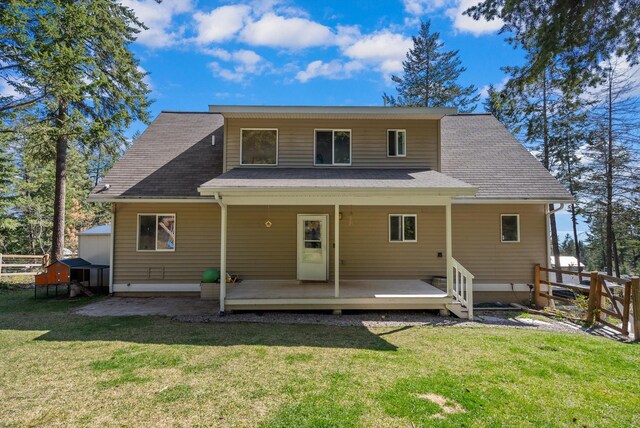 back of house with fence, a yard, and a shingled roof