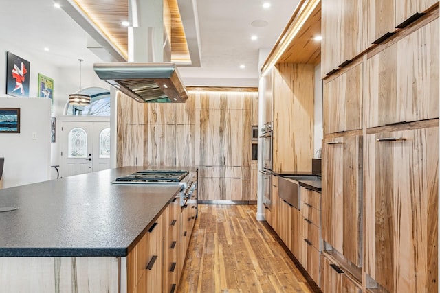 14 Buffalo Hill Cir, Kalispell, MT 59901 - kitchen with dark countertops, island exhaust hood, light wood-type flooring, light brown cabinetry, and recessed lighting