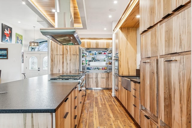 14 Buffalo Hill Cir, Kalispell, MT 59901 - kitchen with island exhaust hood, dark countertops, light wood finished floors, modern cabinets, and light brown cabinets