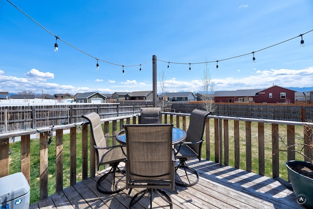 deck featuring a residential view, a lawn, outdoor dining area, and a fenced backyard