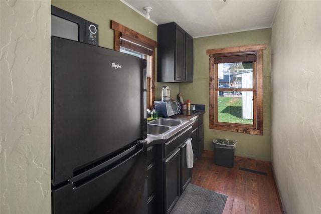 916 2nd St E, Whitefish, MT 59937 - kitchen with dark wood-type flooring, crown molding, dark countertops, freestanding refrigerator, and dark cabinets