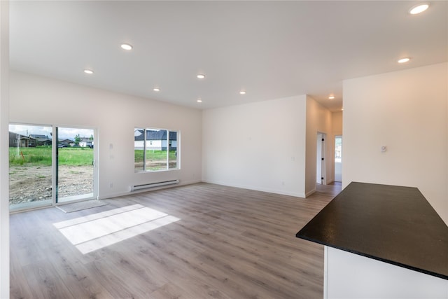 209 Pearl St, Ennis, MT 59729 - unfurnished living room with a baseboard heating unit, healthy amount of natural light, light wood-style flooring, recessed lighting, and baseboards