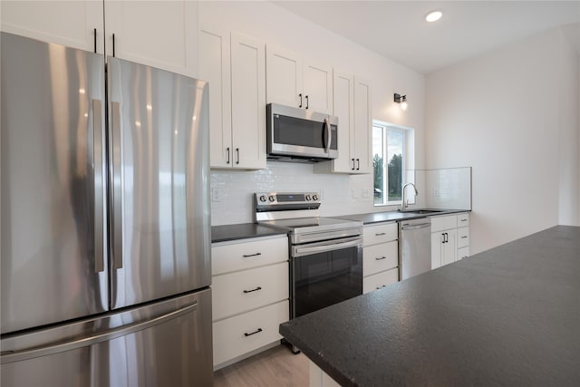 209 Pearl St, Ennis, MT 59729 - kitchen with stainless steel appliances, dark countertops, a sink, decorative backsplash, and white cabinetry