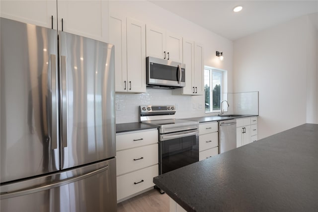 209 Pearl St, Ennis, MT 59729 - kitchen with stainless steel appliances, dark countertops, a sink, backsplash, and white cabinetry