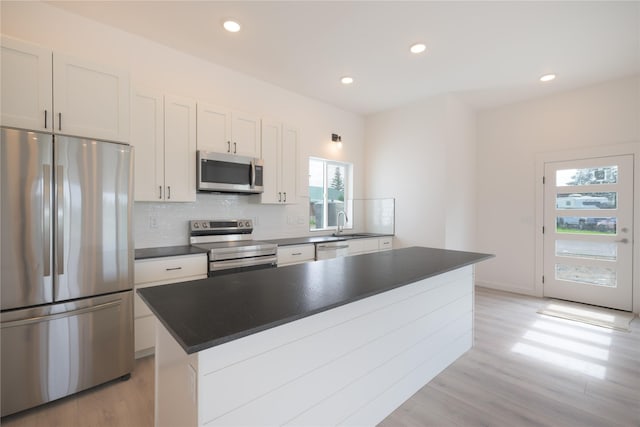 209 Pearl St, Ennis, MT 59729 - kitchen featuring stainless steel appliances, backsplash, light wood-style flooring, dark countertops, and recessed lighting