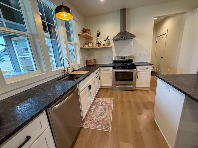 123 Owl Loop, Kalispell, MT 59901 - kitchen with white cabinetry, a sink, light wood-style floors, stainless steel appliances, and wall chimney exhaust hood
