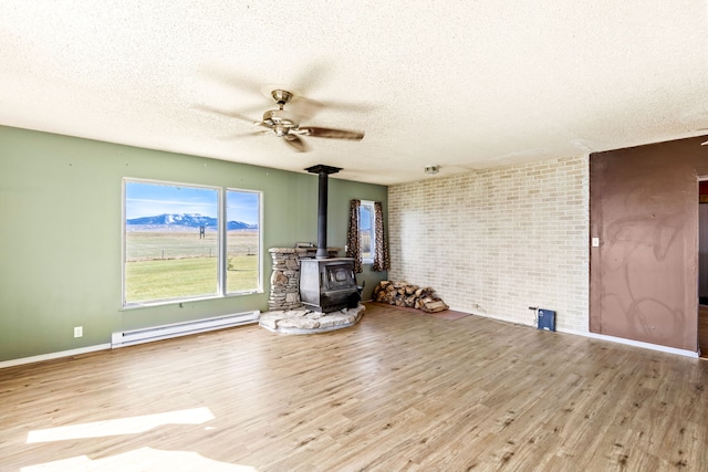 spare room with a wood stove, a textured ceiling, and a baseboard radiator
