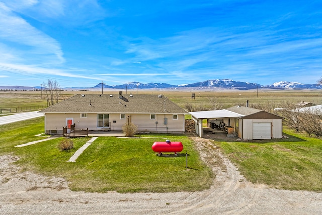 back of house featuring a garage, an outbuilding, a yard, a mountain view, and driveway