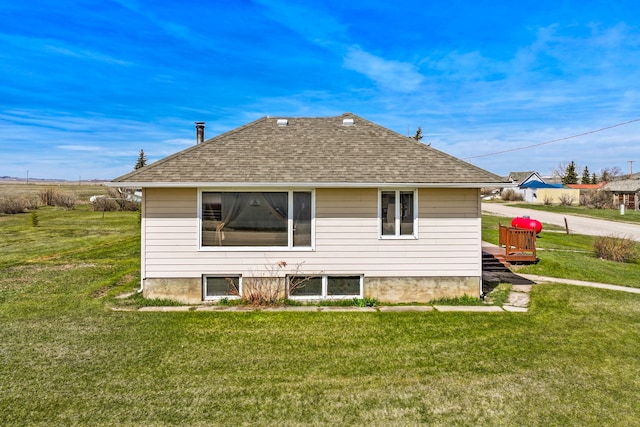 rear view of property with a lawn and a shingled roof