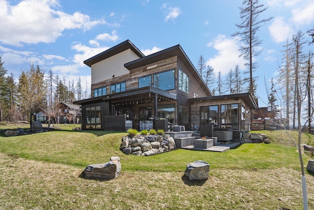 rear view of property featuring a patio, a yard, a sunroom, and stone siding