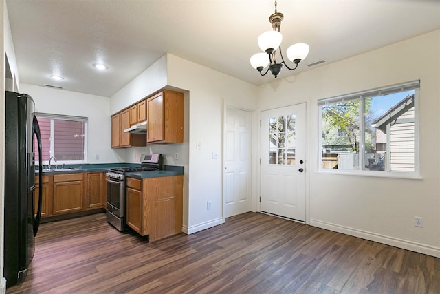 1312 Bridgecourt Way, Missoula, MT 59801 - kitchen featuring stainless steel gas range oven, under cabinet range hood, dark wood-style flooring, brown cabinetry, and dark countertops