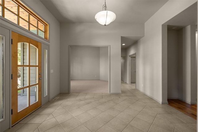 foyer featuring light tile patterned floors, light carpet, and baseboards
