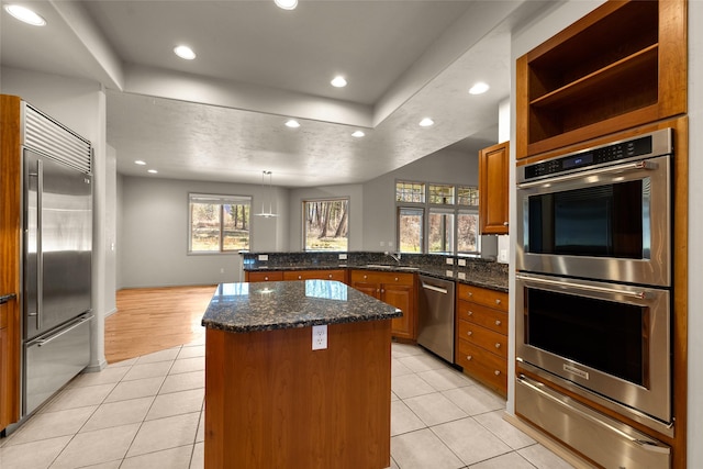 kitchen with light tile patterned floors, stainless steel appliances, a warming drawer, a kitchen island, and a peninsula