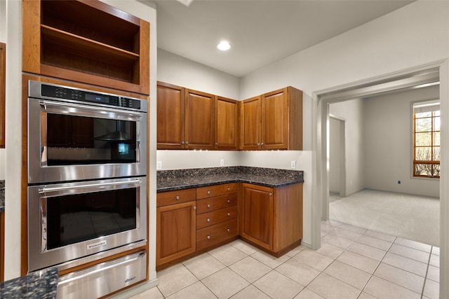 kitchen featuring light carpet, stainless steel double oven, a warming drawer, and brown cabinets