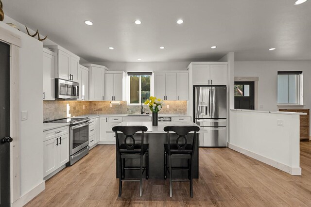 21 Bear Paw Loop, Bigfork, MT 59911 - kitchen featuring appliances with stainless steel finishes, light countertops, a breakfast bar, backsplash, and white cabinets