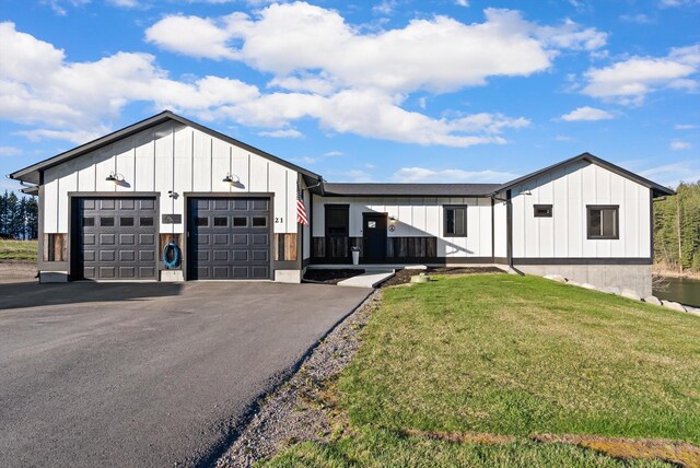 21 Bear Paw Loop, Bigfork, MT 59911 - modern farmhouse featuring board and batten siding, a front lawn, an attached garage, and asphalt driveway