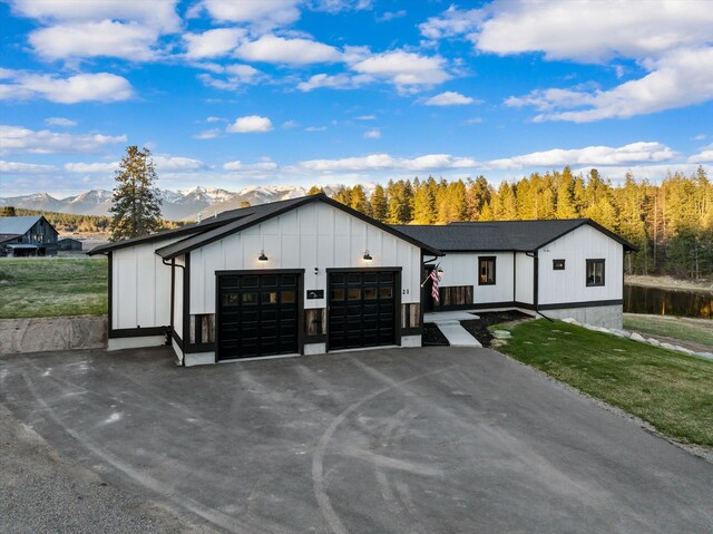 21 Bear Paw Loop, Bigfork, MT 59911 - modern farmhouse style home with board and batten siding, a mountain view, a front lawn, and an attached garage