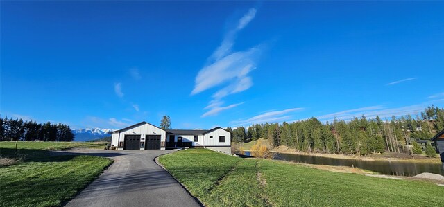 21 Bear Paw Loop, Bigfork, MT 59911 - ranch-style home featuring an attached garage, driveway, a front lawn, board and batten siding, and a water view