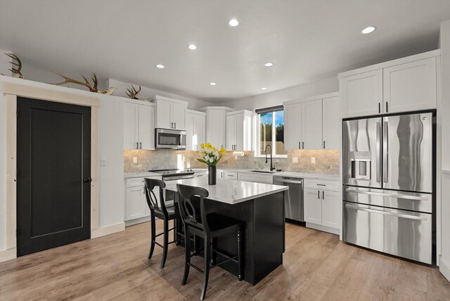 21 Bear Paw Loop, Bigfork, MT 59911 - kitchen featuring stainless steel appliances, a center island, white cabinetry, light countertops, and backsplash
