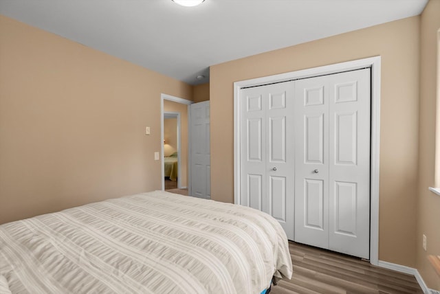 bedroom featuring a closet, wood finished floors, and baseboards